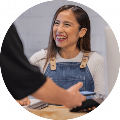 Asian woman in overalls sits at a table smiling at a man in front of her.