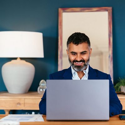 Hispanic businessman making a video call on his laptop in a home office.